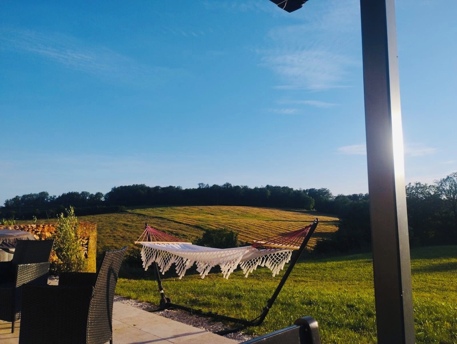 En hængekøje på en terrasse med udsigt over en græsplæne.