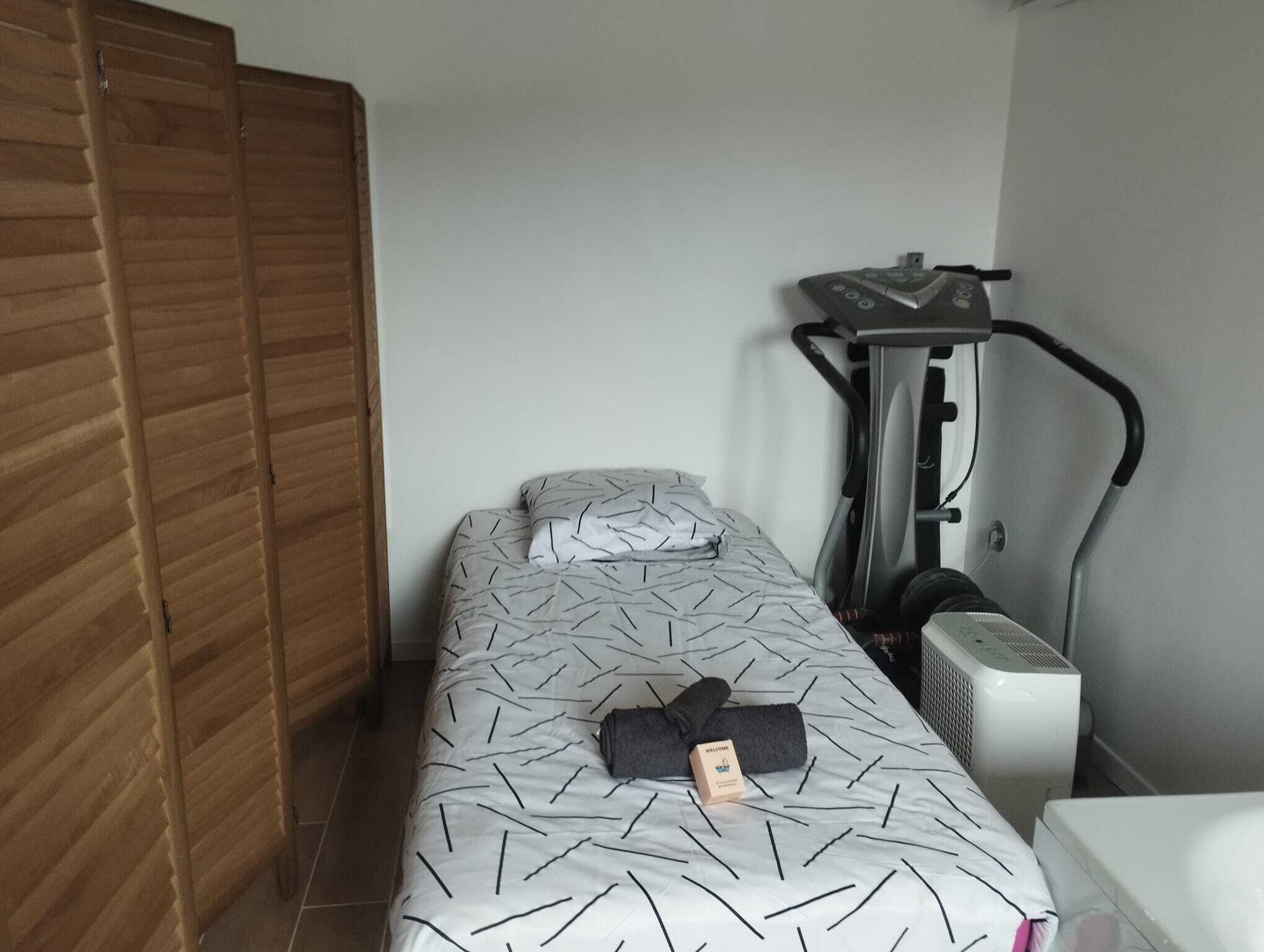 Une chambre à coucher avec un lit, un tapis de course et une armoire en bois.