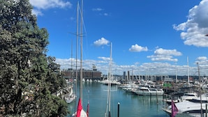 A marina with multiple boats docked, a clear blue sky, and a view of a building in the background. - Viaduct's Big Balcony Breathtaking Views (Auckland)