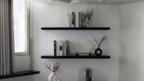 Una parete con tre mensole nere, ognuna con libri e oggetti decorativi.