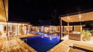 A modern outdoor pool area with wooden decking, a lounge area with seating, and a covered patio. - Trees and Fishes Private Retreat (Port-Havannah)
