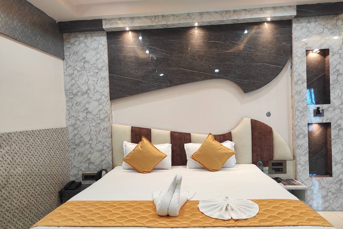 A hotel room with a large bed, marble walls, and a modern design.