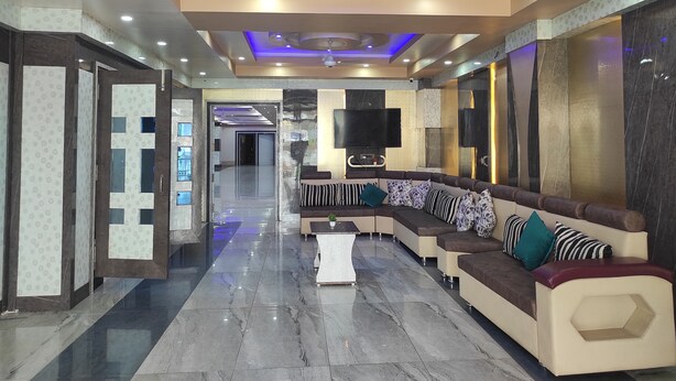 Un rebedor d'hotel modern amb un sofà corbat, una televisió de pantalla plana i un sostre amb il·luminació encastrada i un lluminari circular.