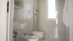 Un baño con ducha envuelta en vidrio, lavamanos y retrete.