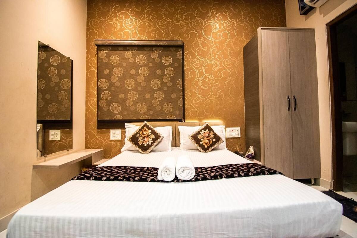 A hotel room with a large bed, two bedside tables, a wardrobe, and a mirror on the wall.