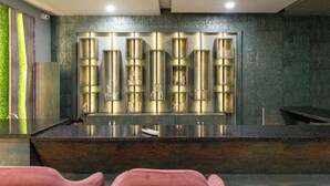 A modern kitchen with a central island, two pink chairs, and a decorative wall panel. - Hotel 7PM (Shaheed Bhagat Singh Nagar)