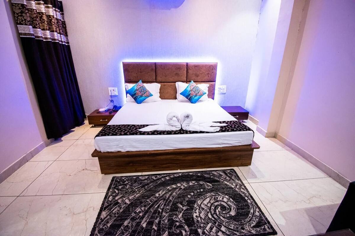 A neatly made bed with a white and patterned bedspread, two pillows, and a decorative towel arrangement.