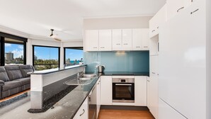 Een moderne keuken met witte kasten, een Bosch oven en een uitzicht op de stad door grote ramen.