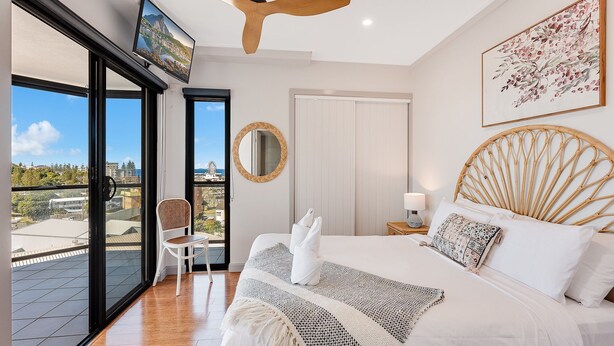 Een slaapkamer met een bed, een stoel, een spiegel en een televisie.