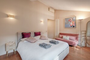 Une chambre à coucher moderne avec un grand lit, un canapé rose et un tableau représentant un personnage de dessin animé.