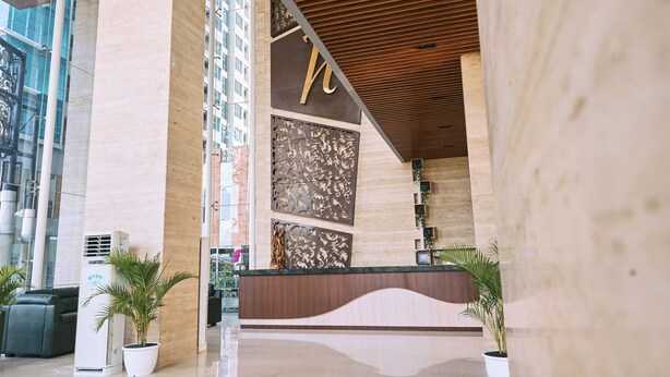 Una moderna zona de recepción con un mostrador de madera, paneles decorativos grandes y plantas en macetas.