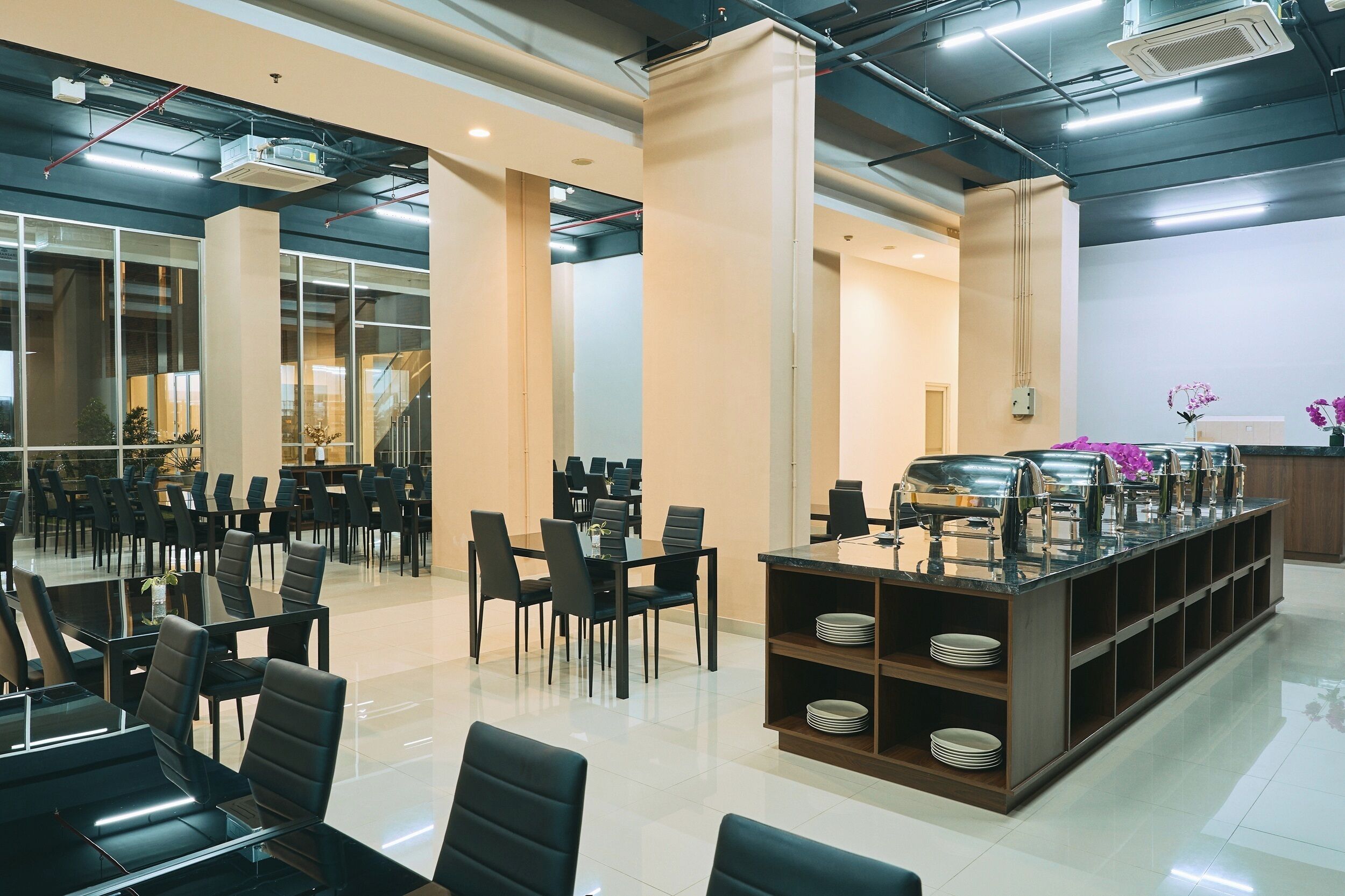 A modern dining area with tables and chairs, a buffet station, and a view of the interior space.
