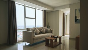 Una sala de estar moderna con un sofá, una mesa de centro y grandes ventanales con vista a la ciudad.