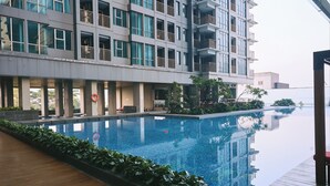 Un hotel moderno con una amplia piscina cubierta, una terraza de madera y vistas a un edificio de gran altura.