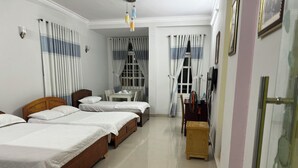 A hotel room with three wooden beds, a small table, and a chair.