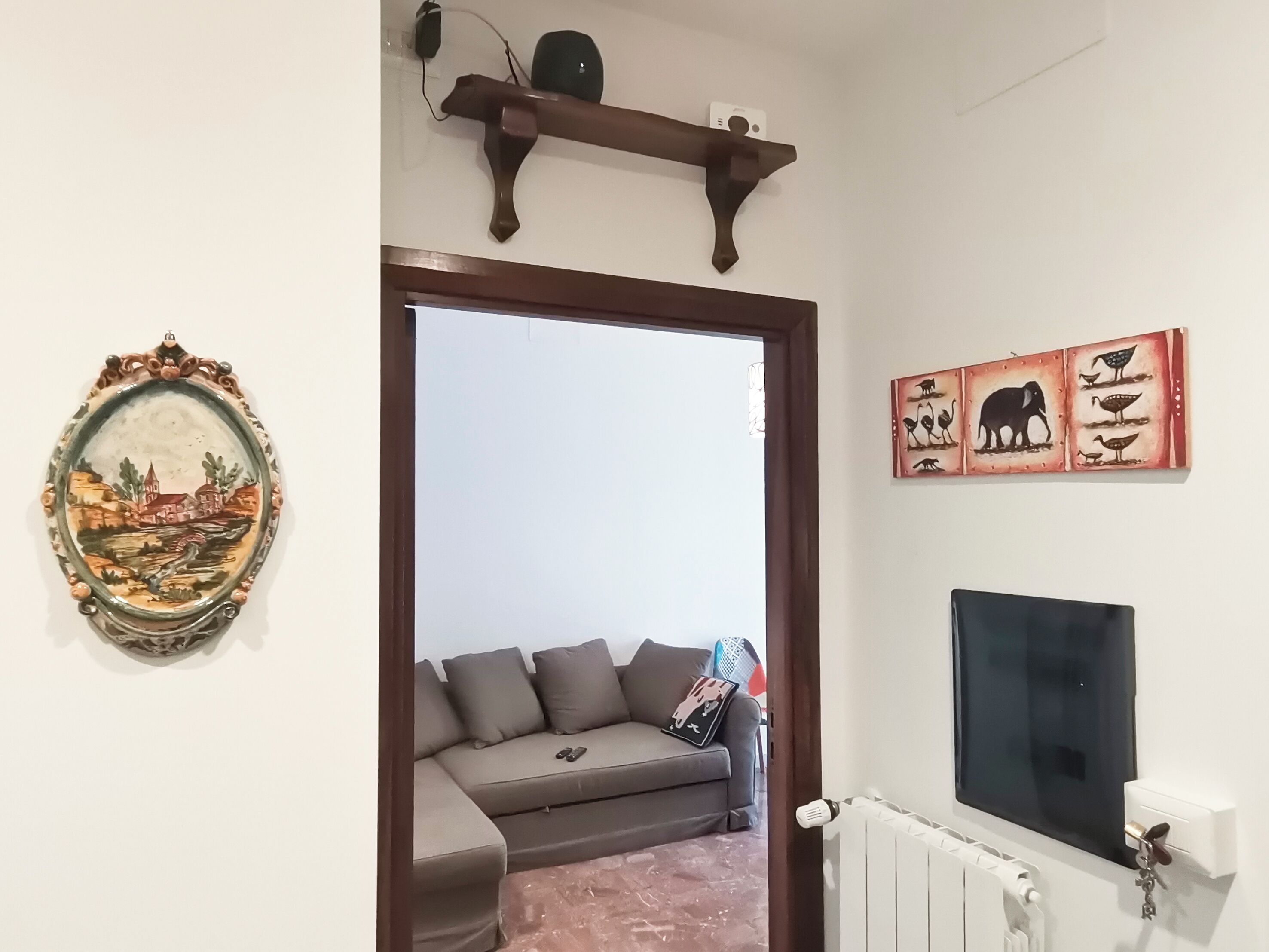 A living room with a sofa, a TV, and wall art.