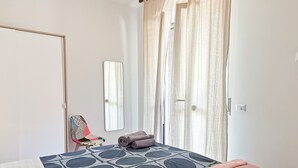 A bedroom with a bed, a chair, a mirror, and curtains. - Naples on foot (Napoli)