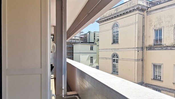 A balcony with a view of adjacent buildings, including a building with a balcony and a building with a window. - Naples on foot (Napoli)