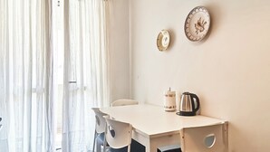 A dining area with a white table, four chairs, a kettle, and two wall-mounted plates. - Naples on foot (Napoli)