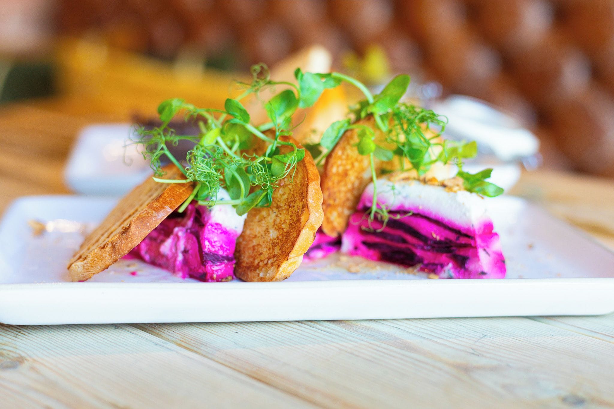 A white rectangular plate with a layered food item, garnished with green herbs.