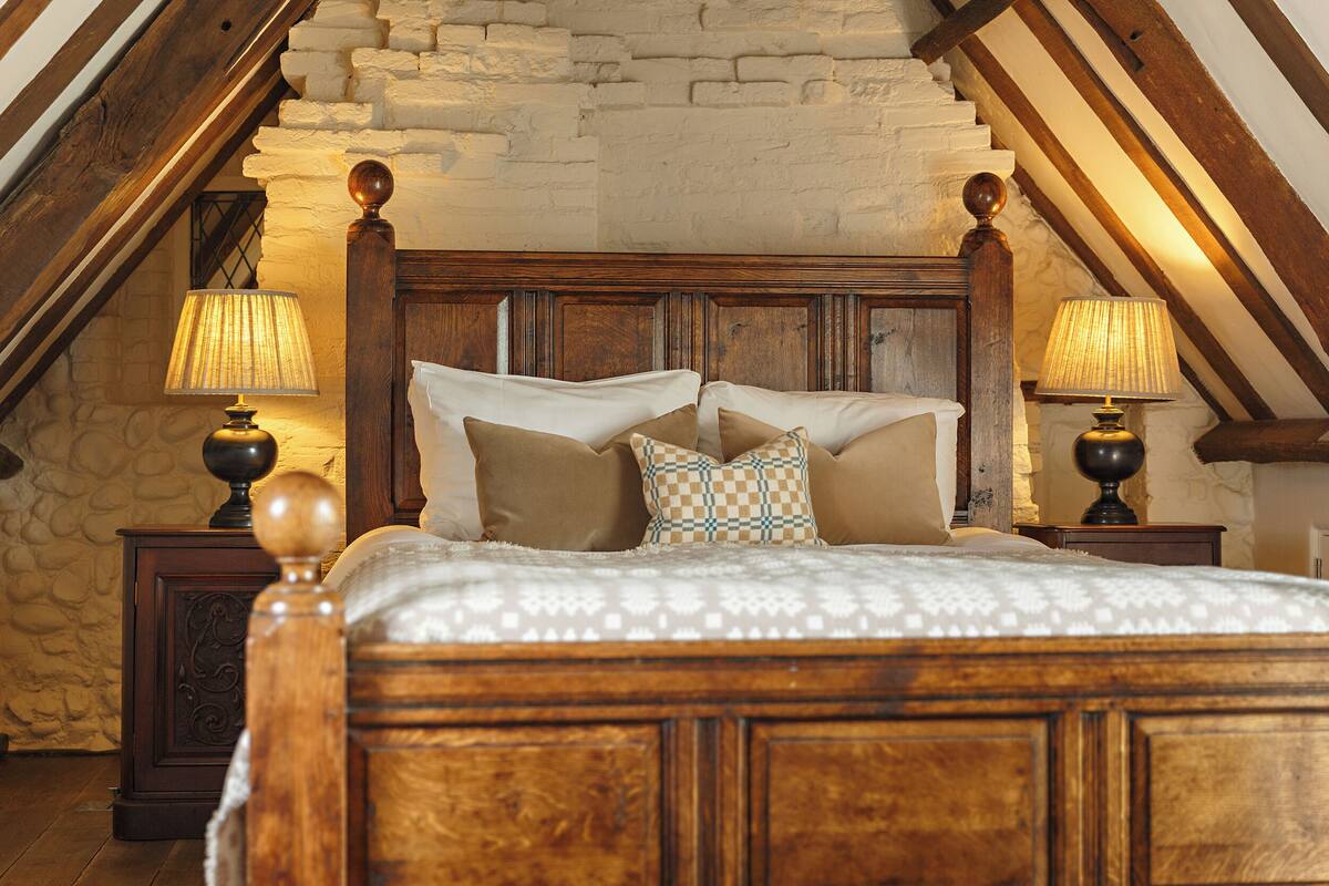 A bedroom with a wooden bed, two nightstands, and a stone wall.