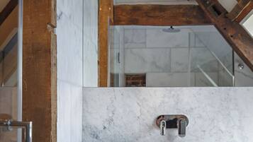 A bathroom with a white sink, marble walls, and wooden beams.