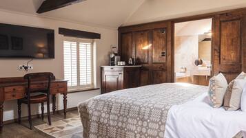 A bedroom with a large bed, a desk, a chair, a wardrobe, and a bathroom visible through an open door.
