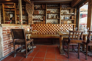 Un restaurante acogedor con pared de ladrillo, estantes de madera y un banco acolchado.