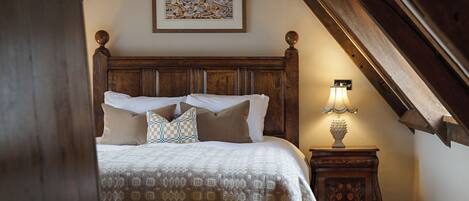 A bedroom with a wooden headboard, a patterned bedspread, and a nightstand with a lamp.