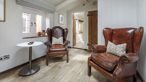 A room with two leather armchairs, a small round table, and a wooden floor. - Byfords  (Holt)