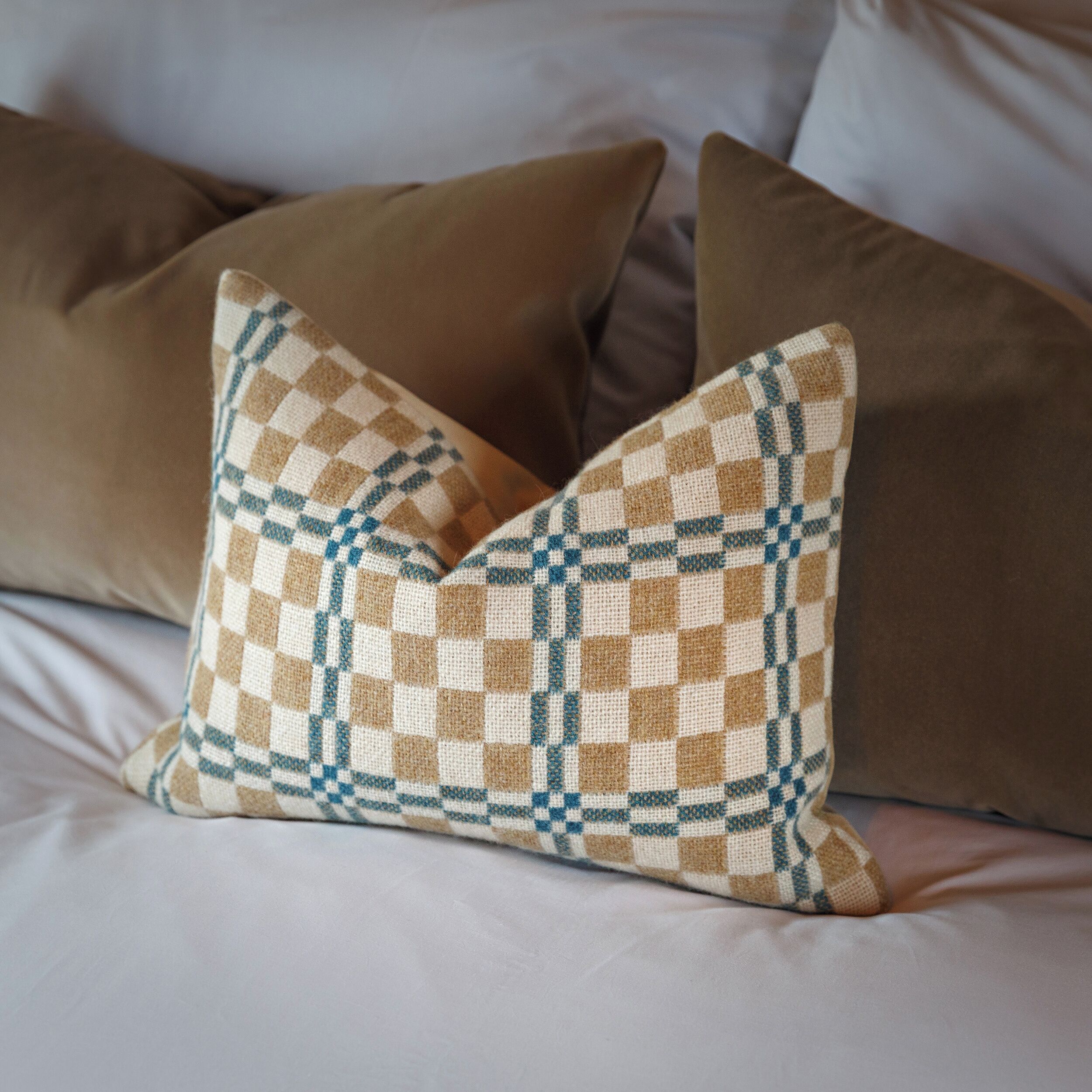 A bed with pillows, one with a checkered pattern.