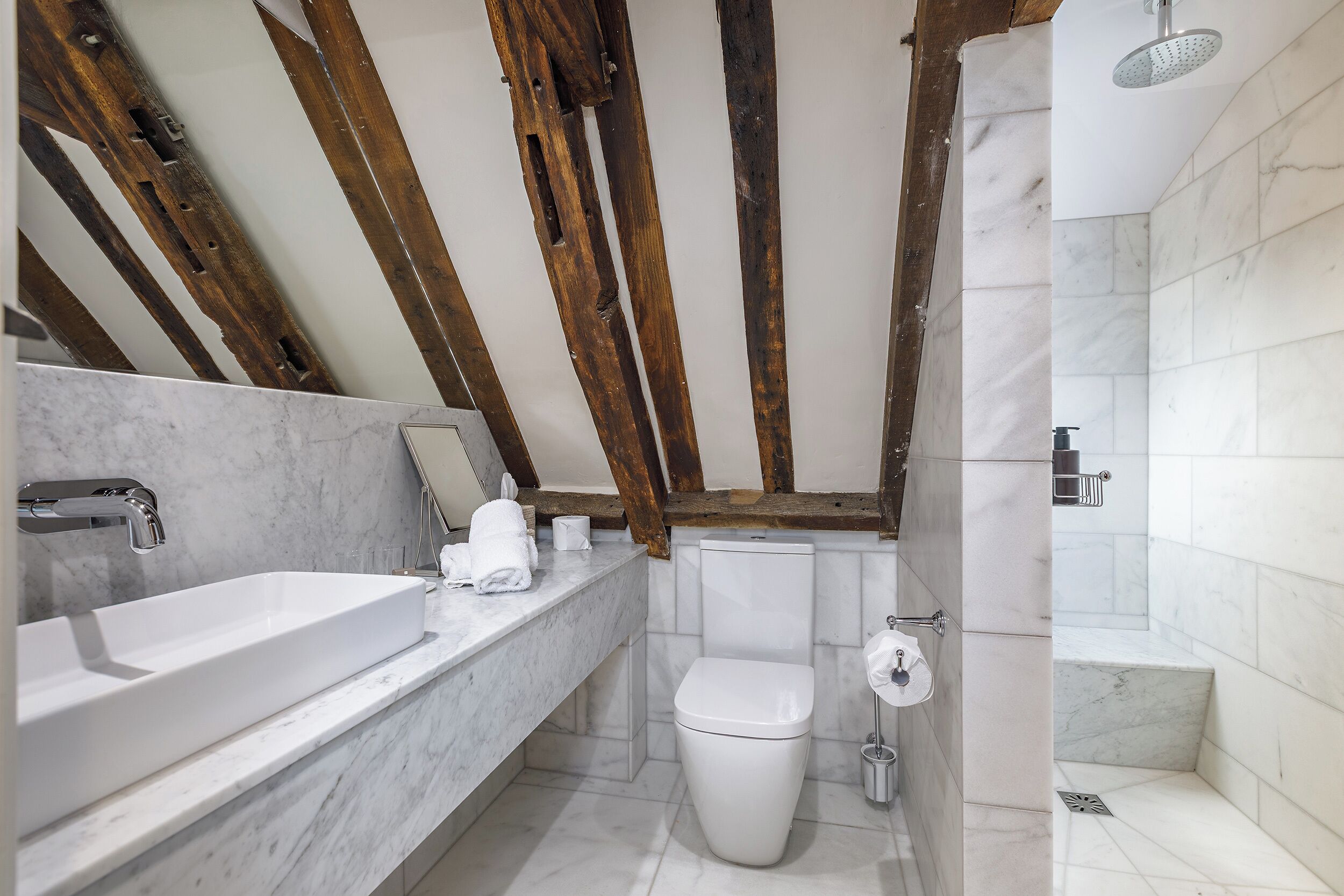 Une salle de bain avec un lavabo en marbre, des toilettes blanches et un espace douche.