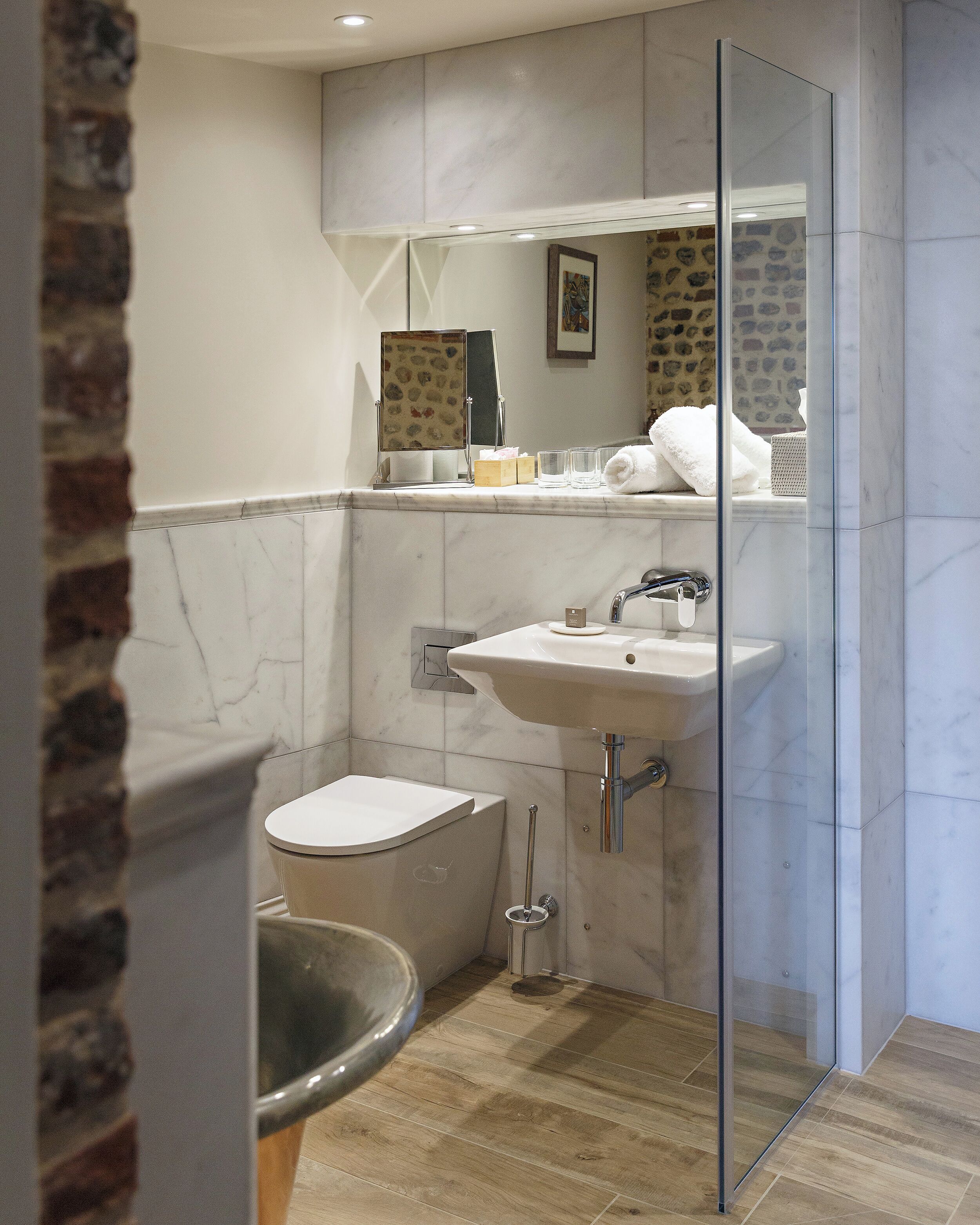 Un baño moderno con cabina de ducha de vidrio, un lavabo blanco y un inodoro.