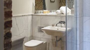 Un baño moderno con cabina de ducha de vidrio, un lavabo blanco y un inodoro.