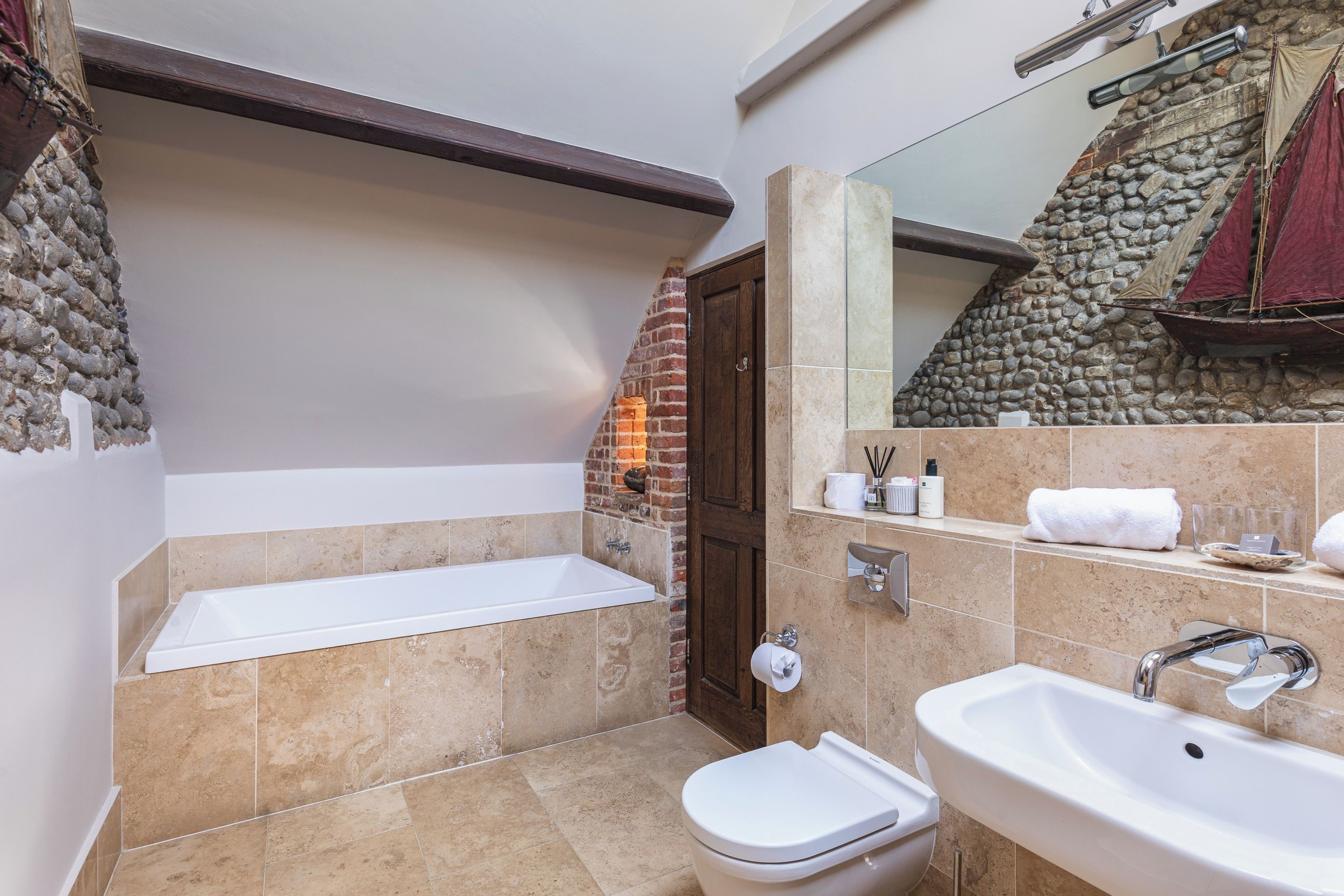 A bathroom with a bathtub, a sink, and a toilet. There is a mirror above the sink and a towel rack.
