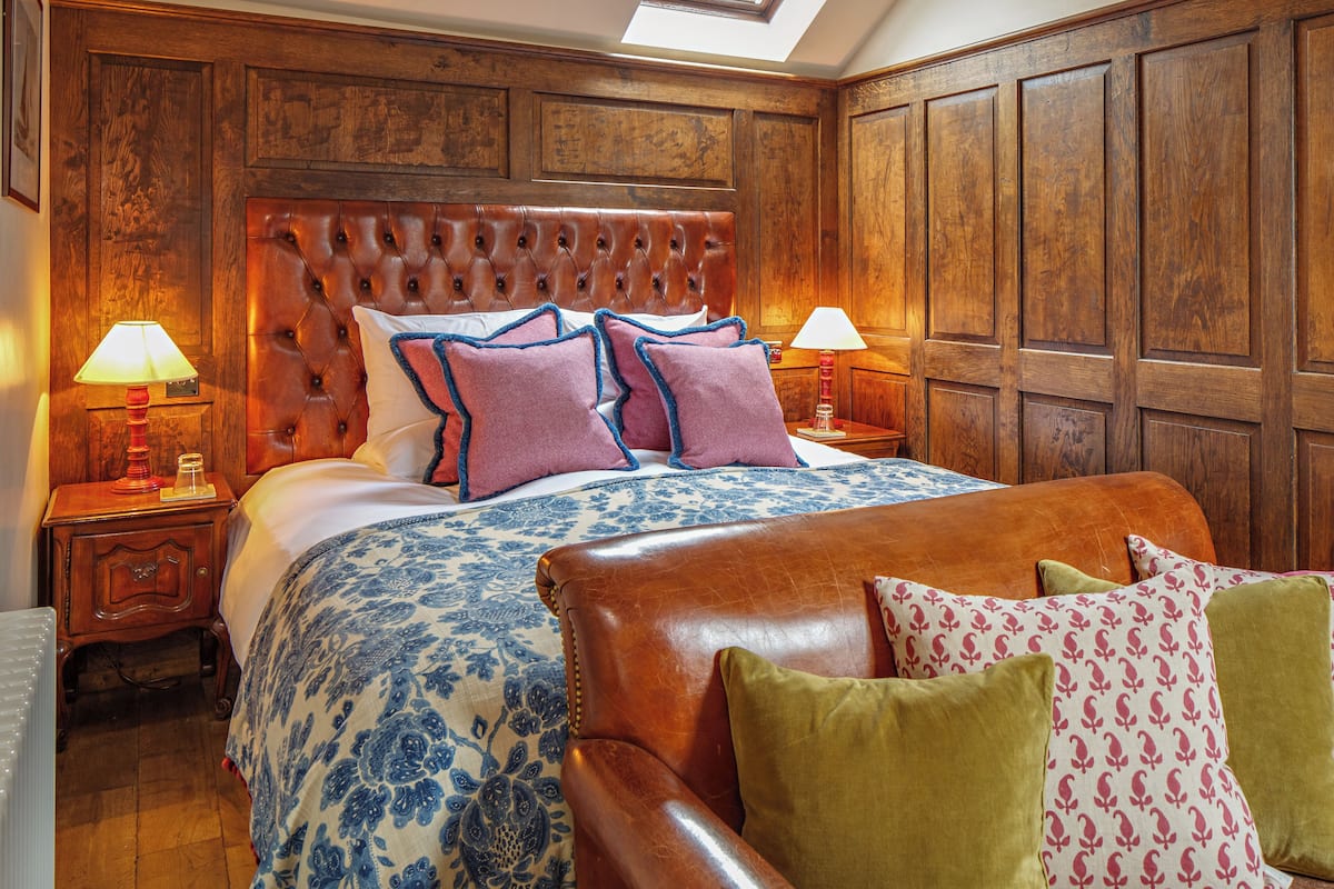 A bedroom with a large bed, wooden headboard, and two bedside tables with lamps.