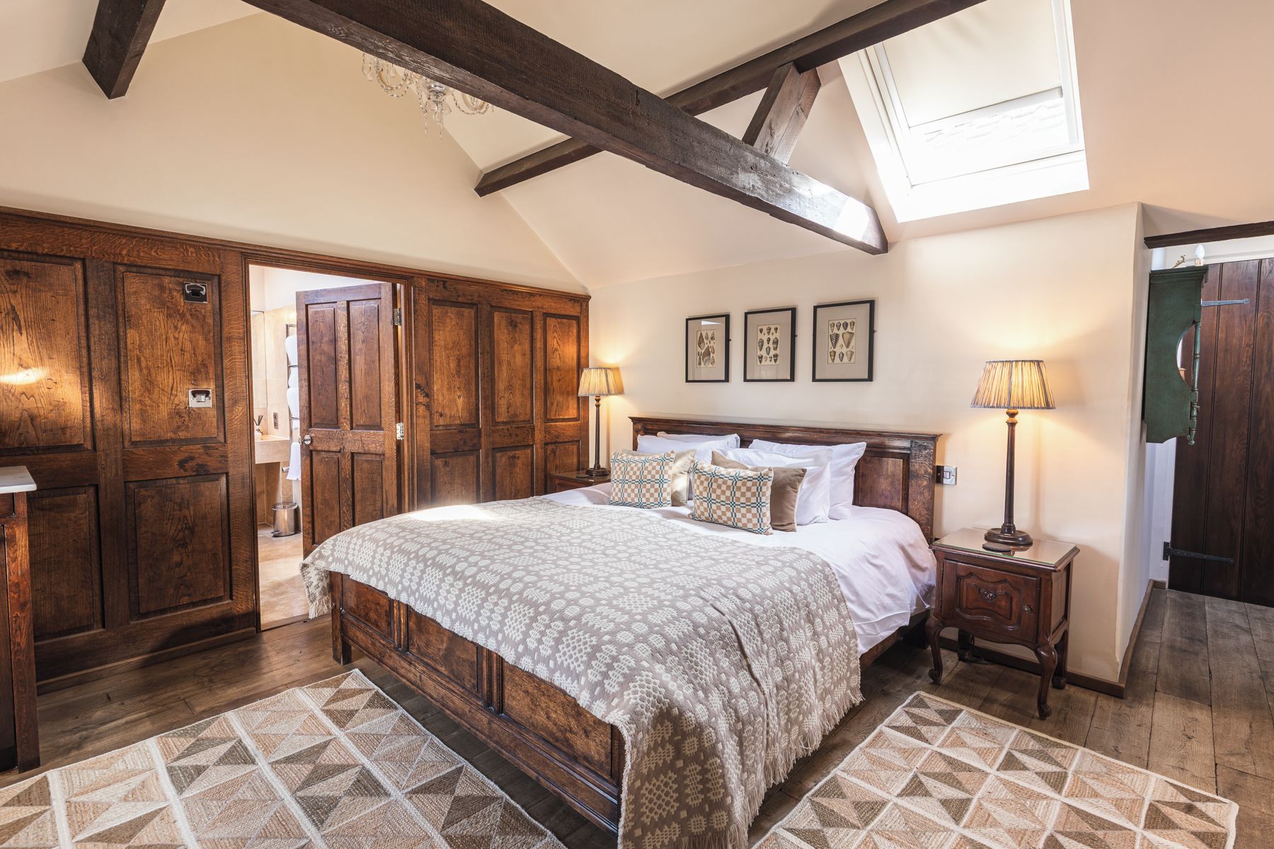 A bedroom with a large bed, wooden wardrobe, and a chandelier.
