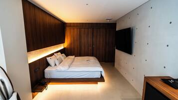 Un dormitorio moderno con cama, mesita de noche y televisor montado.