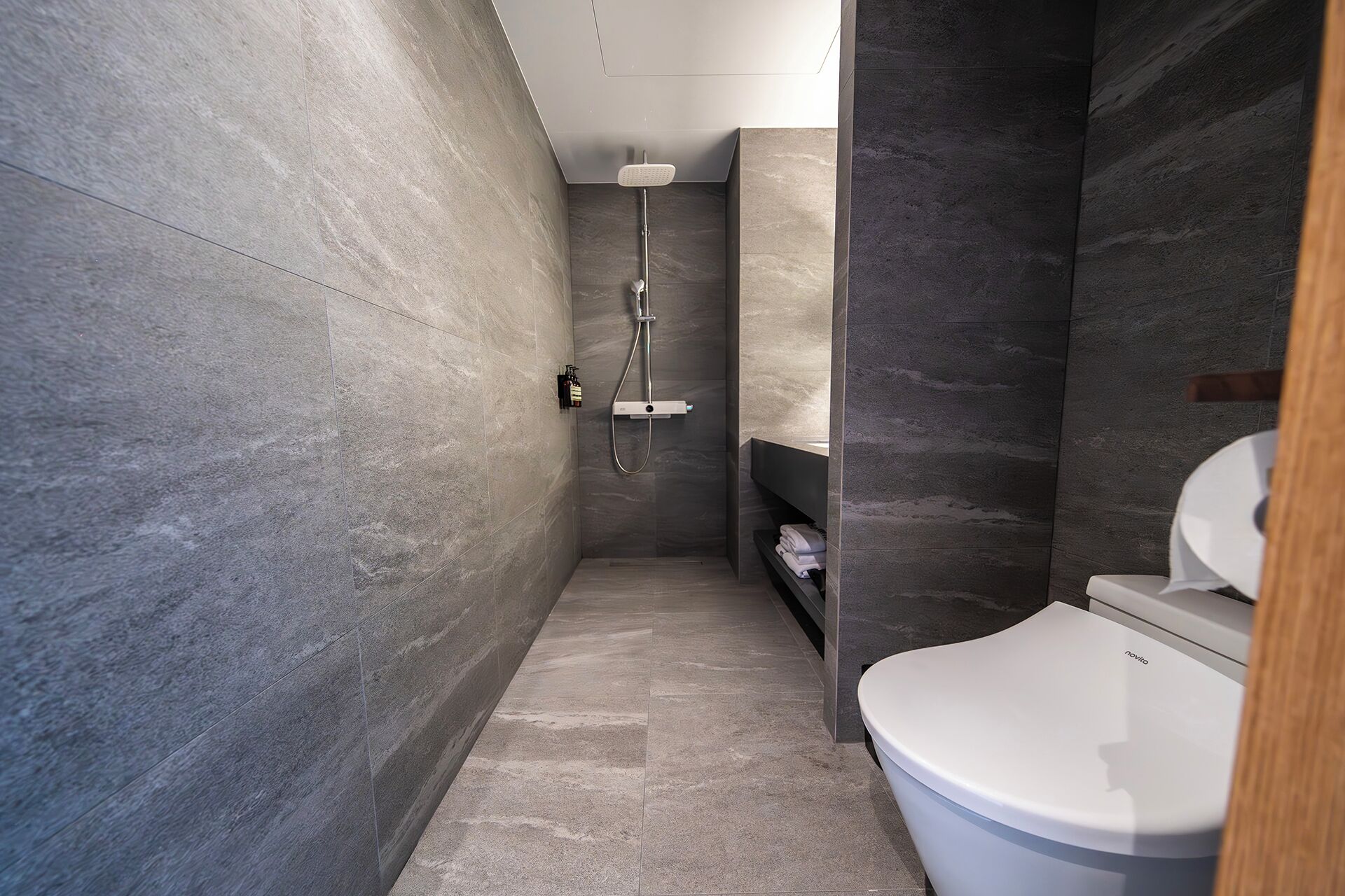 Un baño moderno con ducha, inodoro y estante empotrado.