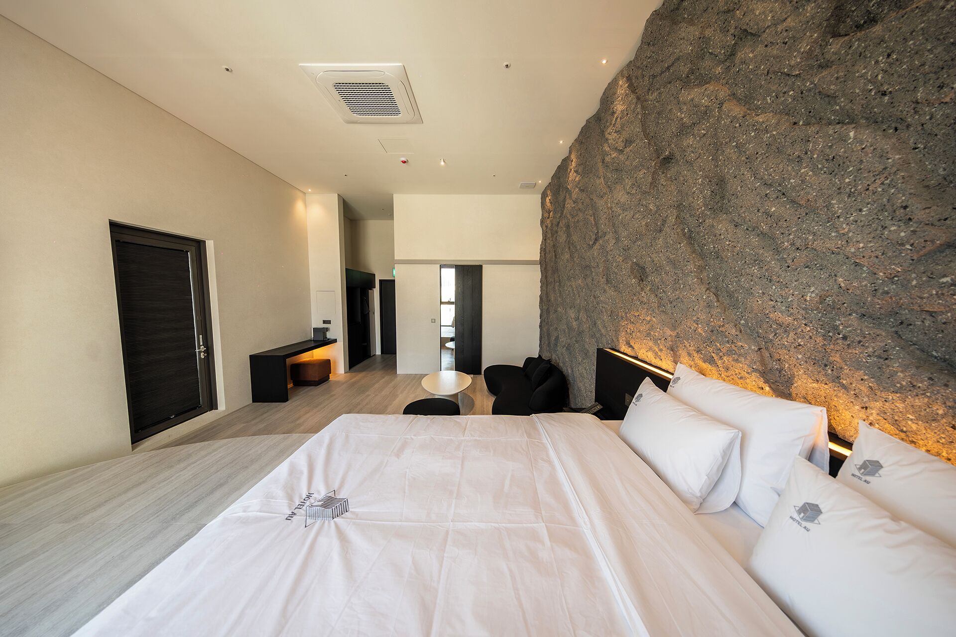 Un dormitorio moderno con una cama grande, una pared de acento de piedra y un diseño minimalista.