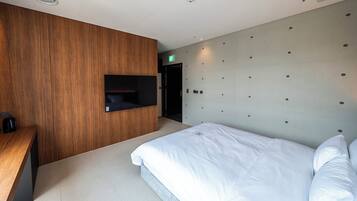Una habitación de hotel moderna con una pared de acento de madera, una estantería empotrada, una cama con ropa de cama blanca y una lámpara de pared.