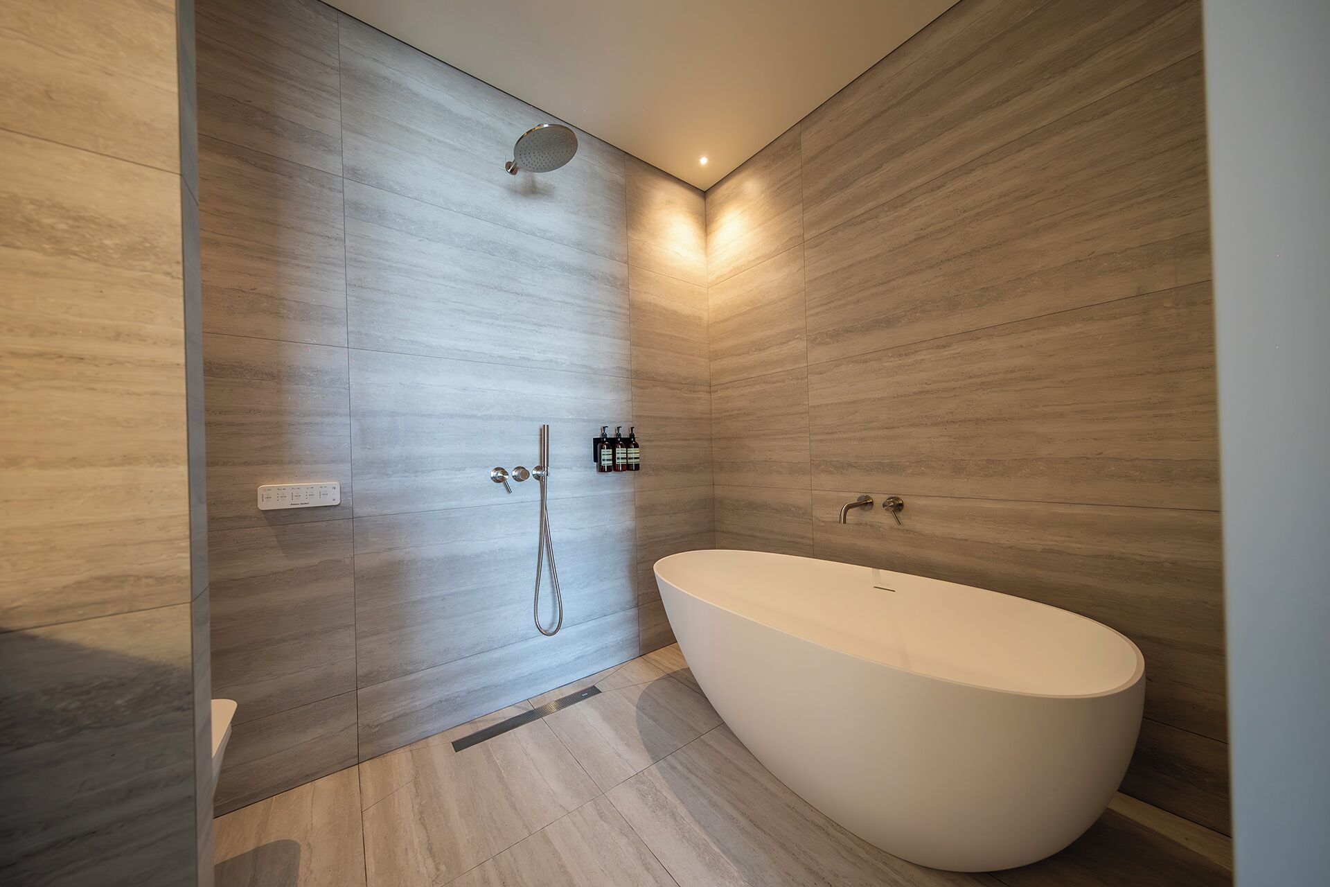 Un baño moderno con una bañera independiente, un cabezal de ducha de mano y un grifo empotrado.