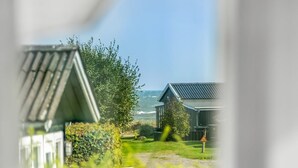 Une vue sur la côte avec deux cabanes, un sentier herbeux et une étendue d’eau.