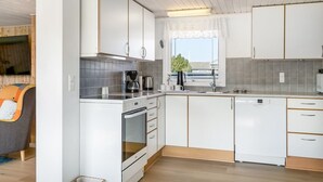 Une cuisine moderne avec des armoires blanches, un four encastré et un lave-vaisselle.
