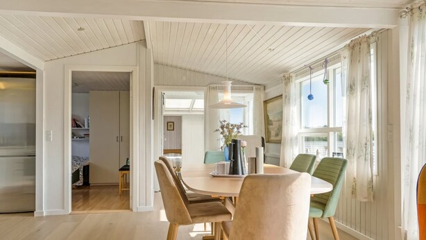 Un coin repas comprenant une table ronde, quatre chaises et un luminaire suspendu.