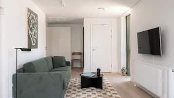 Una sala de estar moderna con un sofá verde, una mesa de centro negra y una alfombra a cuadros.