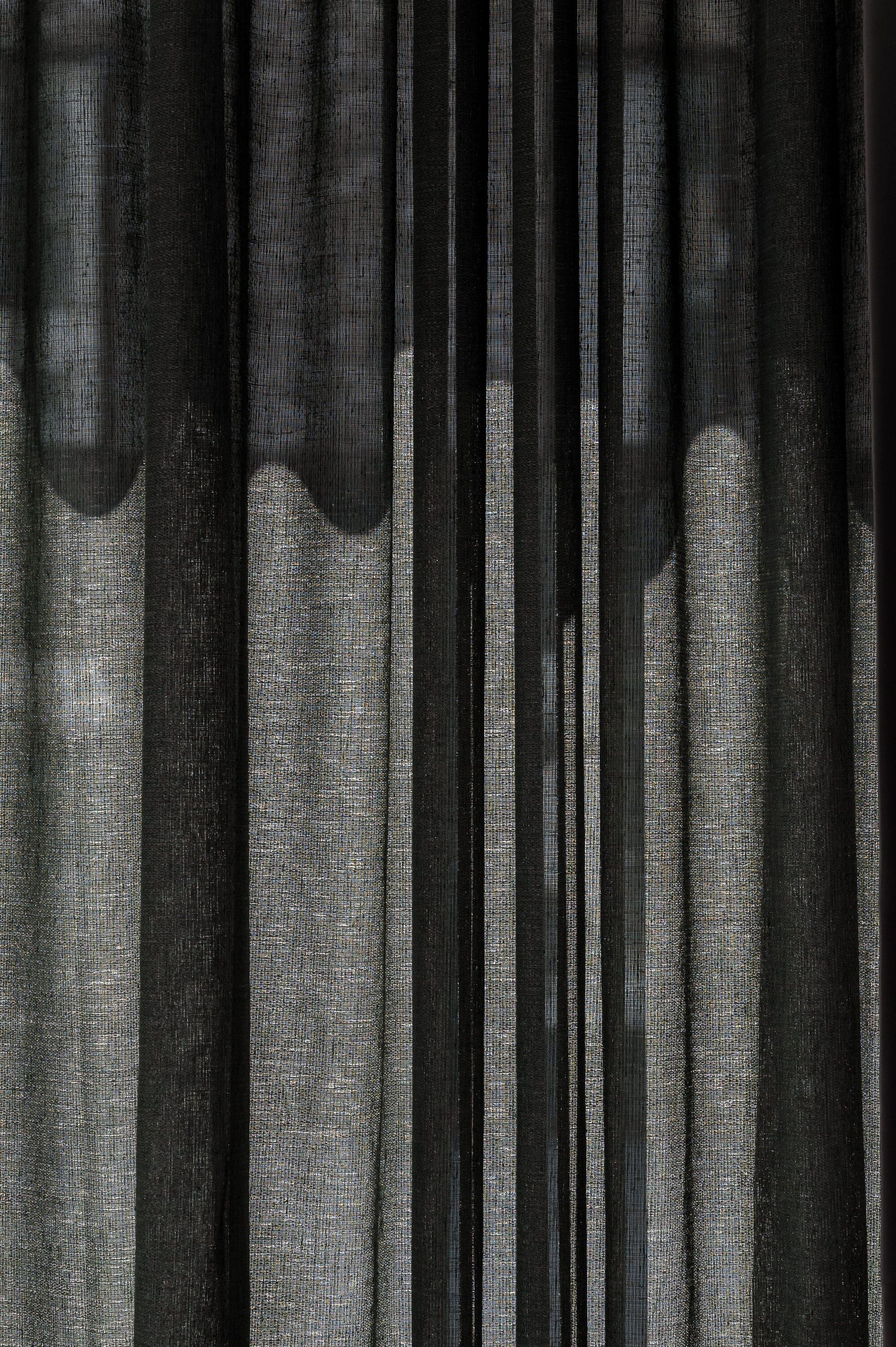 A close-up of a curtain with a textured fabric and a sheer overlay.