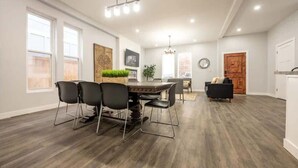 Ein geräumiges Wohnzimmer mit Essbereich, großen Fenstern und einer modernen Deckenleuchte.