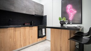 Une cuisine moderne avec des meubles en bois, un plan de travail noir et un néon en forme de flamant rose.