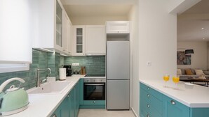 Eine moderne Küche mit türkisfarbenen Schränken, einem Edelstahlkühlschrank und einer weißen Arbeitsplatte.